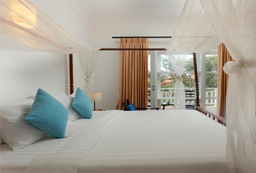 una camera da letto con un grande letto bianco con cuscini blu di Amber Angkor Villa Hotel & Spa a Siem Reap