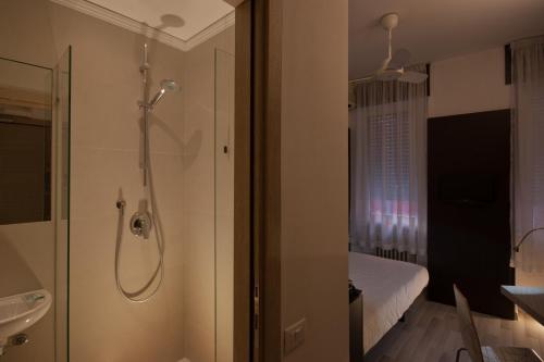uma casa de banho com um chuveiro, uma cama e um lavatório. em Genius Hotel Downtown em Milão