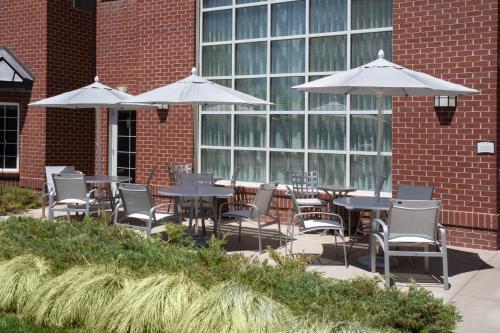 a patio with tables and chairs and umbrellas at Staybridge Suites Denver International Airport by IHG in Denver