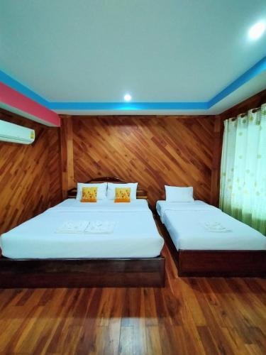 two beds in a room with wooden walls and wood floors at Palmsuay Resort in Ban Dong Klang