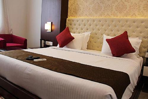 Hotel Taj Heights في آغْرا: سرير كبير في غرفة الفندق مع وسائد حمراء