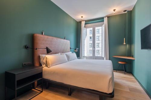 1 dormitorio con cama blanca y pared verde en Uma Suites Atocha en Madrid