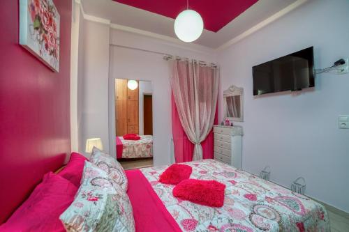 a bedroom with pink walls and a bed with red pillows at Blue Boutique Apts in Amoudara Herakliou