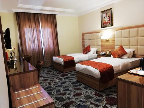 ジッダにあるRoshan Al Azhar Hotelのベッド2台とデスクが備わるホテルルームです。