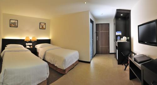 Habitación de hotel con 2 camas y TV de pantalla plana. en ERNES Hotel, en Perai