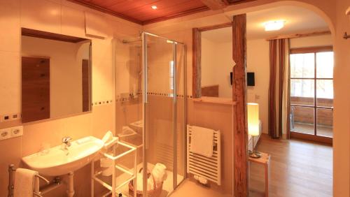 a bathroom with a sink and a glass shower at Naturhotel Lärchenhof in Ramsau am Dachstein