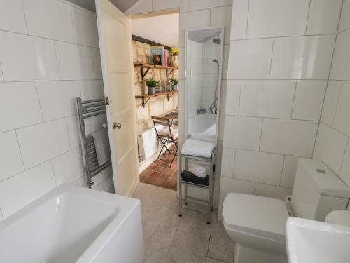 a white bathroom with a toilet and a sink at Thimble Cottage in Cheltenham