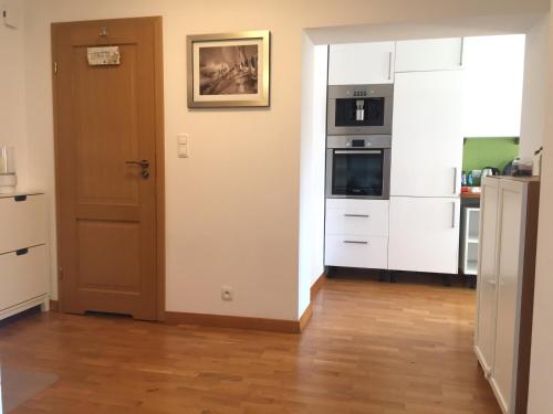 a kitchen with white cabinets and an open door at Fregata Apartment Gdynia in Gdynia