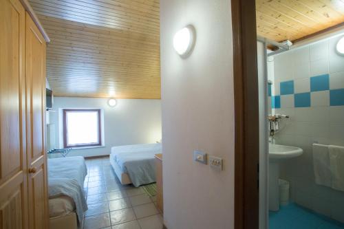 a room with two beds and a bathroom with a sink at Al Bottegon in Tricesimo