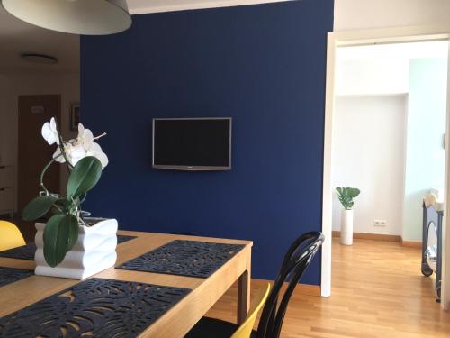 a dining room with a blue wall with a table and a tv at Fregata Apartment Gdynia in Gdynia