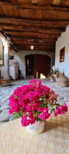 a vase filled with pink flowers in front of a fireplace at Affittacamere Valnascosta in Faedis