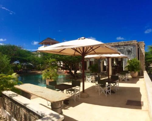 a patio with tables and an umbrella next to a pool at The Majlis Resort in Lamu