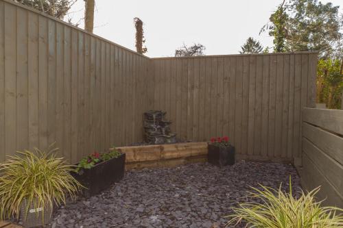 a wooden fence with a fountain in a garden at Thatched Eaves in Ibsley