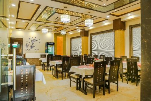 a dining room with tables and chairs and a mirror at Hotel Taj Heights in Agra
