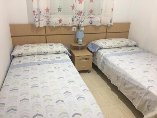 Apartamentos Costa Azahar II في أوروبيسا ديل مار: سريرين يجلسون بجانب بعض في غرفة النوم