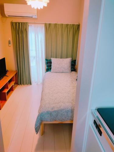 a small bedroom with a bed and a television at MEME Inn与野本町駅前 in Saitama