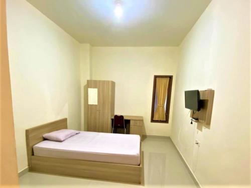 1 dormitorio pequeño con 1 cama y TV en Pondok Bintang, en Biringkanya
