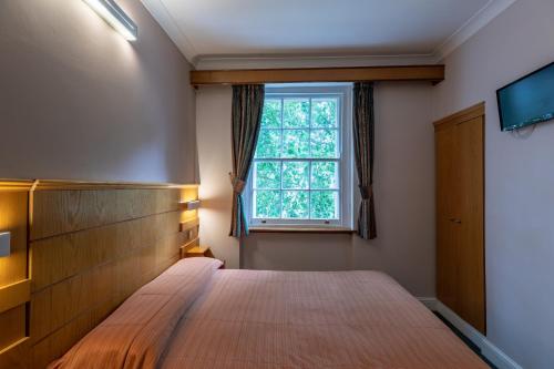 1 dormitorio con cama y ventana en The Nayland Hotel, en Londres