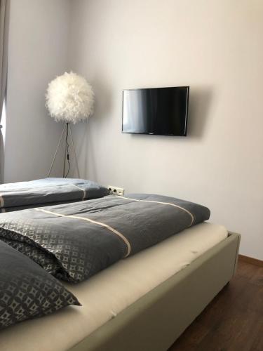 a bedroom with two beds and a flat screen tv on the wall at Wohlfühlen in der Altstadt von Steyr in Steyr