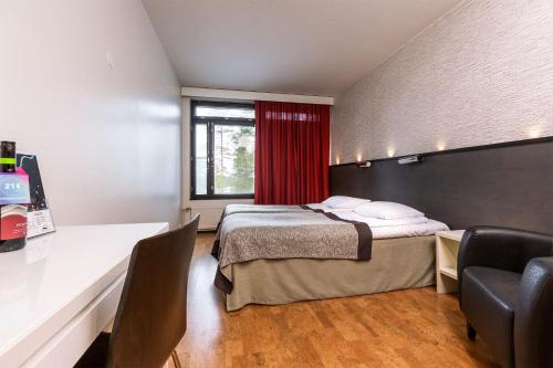 a bedroom with a bed and a desk and a window at Finlandia Hotel Imatran Kylpylä Spa in Imatra