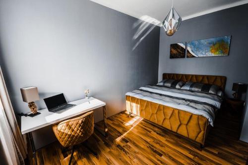 Schlafzimmer mit einem Bett und einem Schreibtisch mit einem Laptop in der Unterkunft Design-Appartement Steyr in Steyr