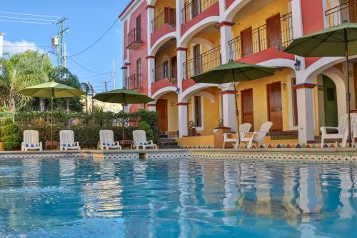 a swimming pool in front of a building with chairs and umbrellas at La Casona Tequisquiapan Hotel & Spa in Tequisquiapan