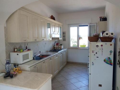 eine Küche mit weißen Schränken und einem weißen Kühlschrank in der Unterkunft Casa in campagna in San Giovanni Suergiu