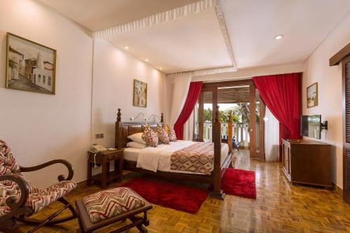 ein Schlafzimmer mit einem Bett und einem Stuhl in einem Zimmer in der Unterkunft Travellers Beach Hotel in Mombasa