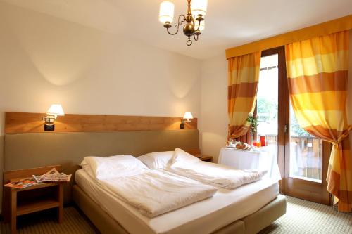 Schlafzimmer mit einem Bett und einem Fenster in der Unterkunft Royal Olympic Hotel in Pinzolo