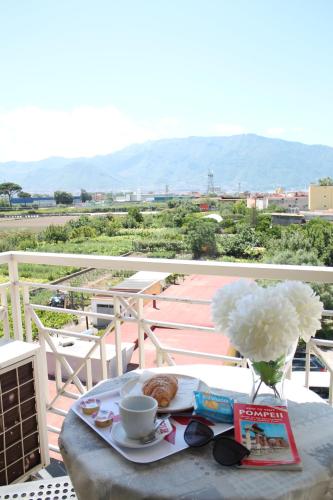 een tafel met een bord eten en een vaas met bloemen bij VesuView Guest House near the Ruins in Pompei