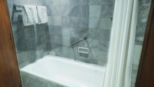 a bathroom with a shower with a white tub at The Jayakarta Yogyakarta Hotel & Spa in Yogyakarta