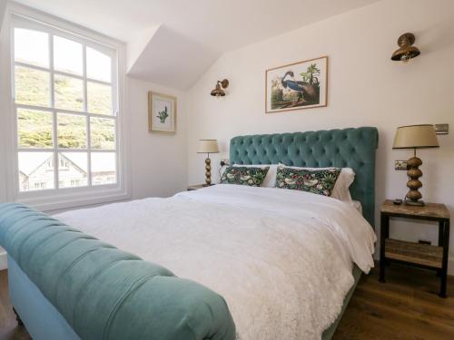 ein Schlafzimmer mit einem großen Bett mit blauem Kopfteil in der Unterkunft Harbour Cottage in Boscastle