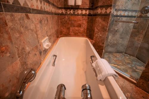 a bathroom with a tub with a shower and a towel at LAOTEL VIENTIANE in Vientiane