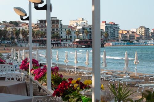 克羅托內的住宿－Palazzotto 902，海滩上设有桌子和白色遮阳伞,还有大海