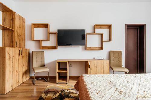 a bedroom with a desk and two chairs and a tv at Hotel Carpati in Gura Humorului