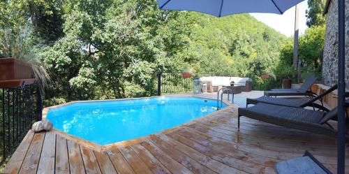 una piscina con due sedie e un ombrellone di L'Ancienne Ecole a Entraygues-sur-Truyère