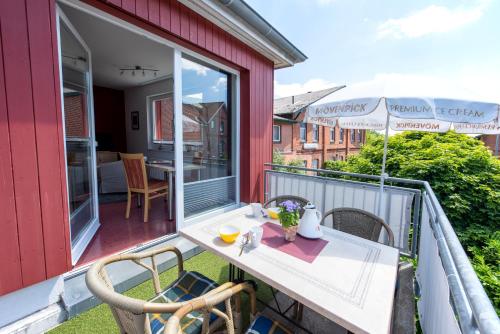 a balcony with a table and chairs and an umbrella at De Kanalkieker Apartmenthaus Meier in Berkenthin