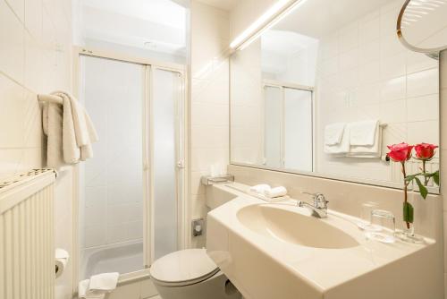 a white bathroom with a sink and a toilet at Pension Rose in Bretzfeld