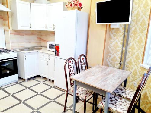 アドレルにあるЦентр Адлера - Квартираの白いキャビネット、テーブルと椅子付きのキッチンが備わります。