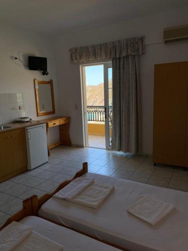 a room with a bed and a kitchen with a window at Eolia beachfront studios in Plakias