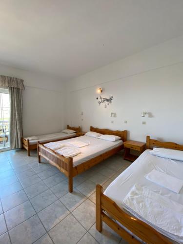 a bedroom with three beds and a window at Eolia beachfront studios in Plakias