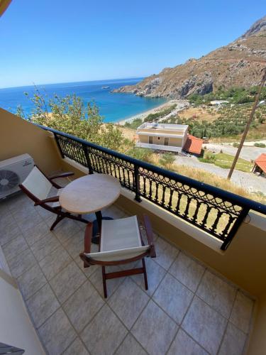 a balcony with a table and chairs and the ocean at Eolia beachfront studios in Plakias