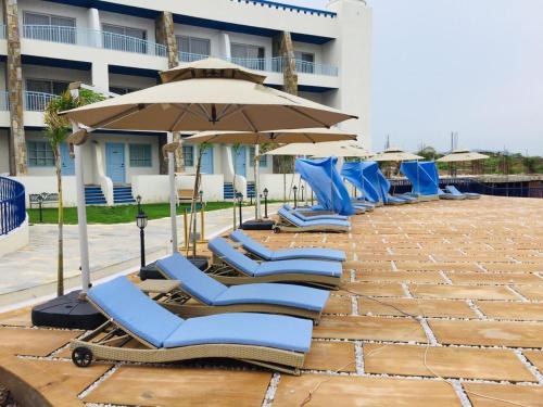 a row of blue lounge chairs and an umbrella at Ramee Royal Resort & Spa - Udaipur in Udaipur
