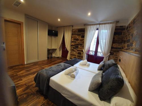 a bedroom with two beds and a brick wall at Albergue Casa Cuartel in Fonsagrada