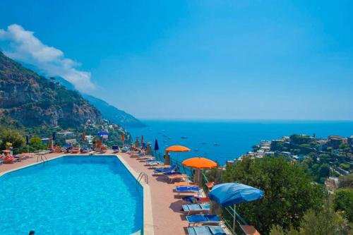 una piscina con sombrillas y sillas y el océano en Casa Giostrello, en Positano