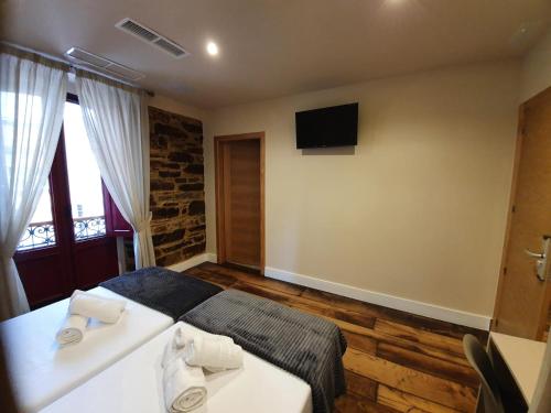 a bedroom with a bed and a television on the wall at Albergue Casa Cuartel in Fonsagrada
