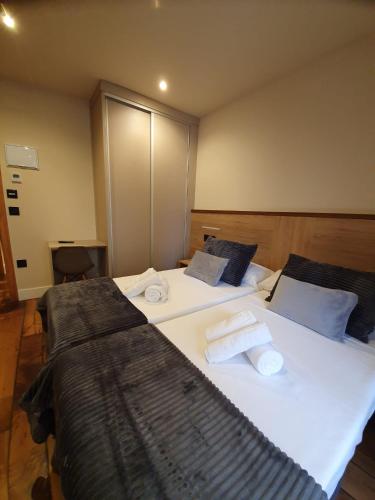two beds in a hotel room with towels on them at Albergue Casa Cuartel in Fonsagrada