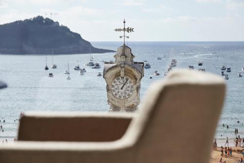 a clock tower on the beach with boats in the water at Hotel Boutique Villa Favorita in Donostia-San Sebastián
