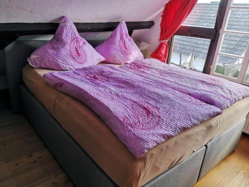 uma cama com um cobertor roxo e almofadas em Ferienhof Schmickerath em Simmerath