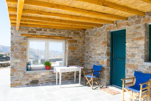 un patio con sillas azules, una mesa y una ventana en Traditional suites in Chora Kythnos #3, en Kithnos